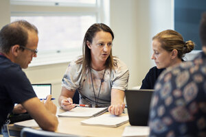 [Translate to English:] Studenter kring ett bord, försjunkna i diskussion.